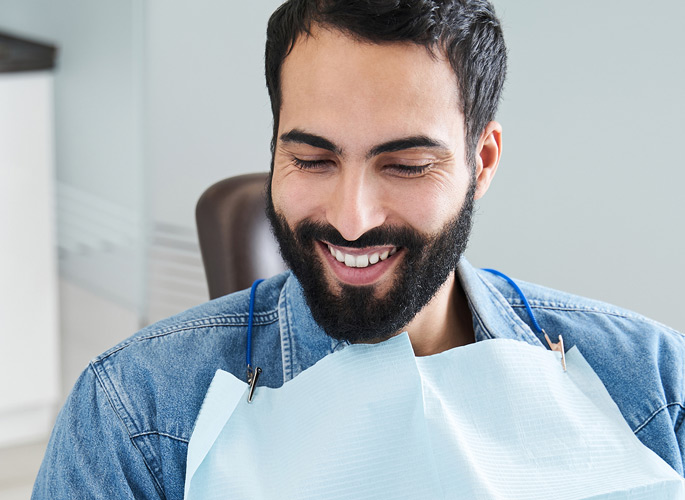 Man smiling and looking down in dental chair